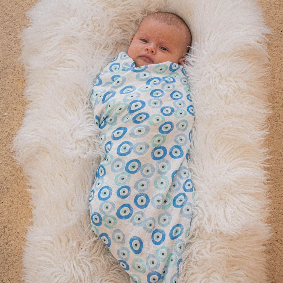baby in a swaddle blanket with blue evil eye print patternbaby in a swaddle blanket with blue evil eye print pattern