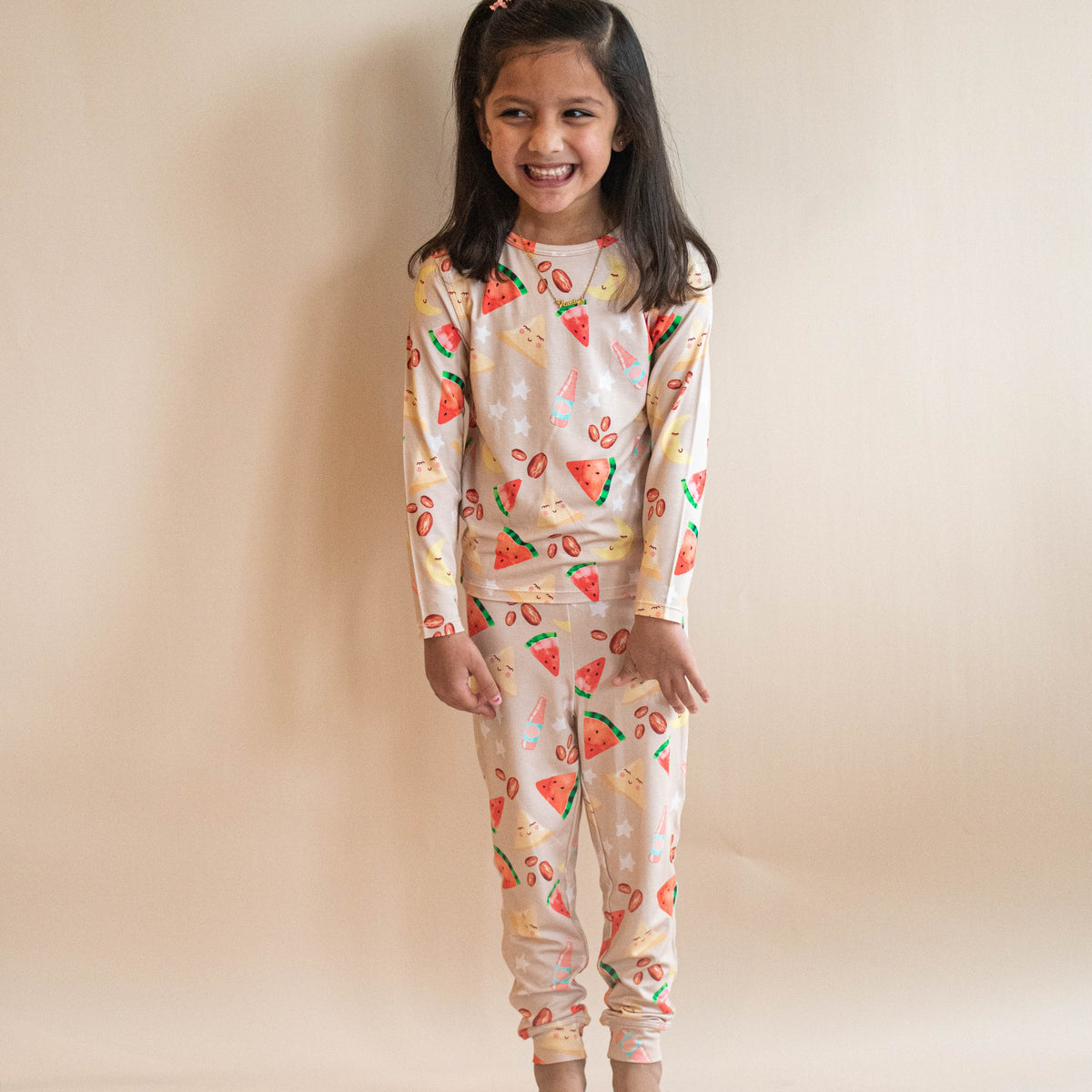 girl standing in oat colored pjs with watermelon and samosas and fruits