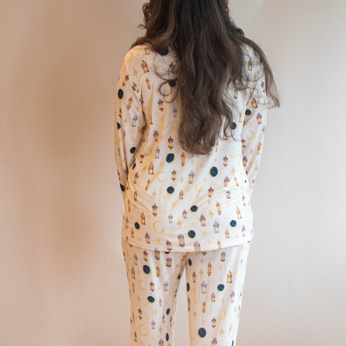woman standing in pjs looking at camera moon and star lanterns all over pajamas