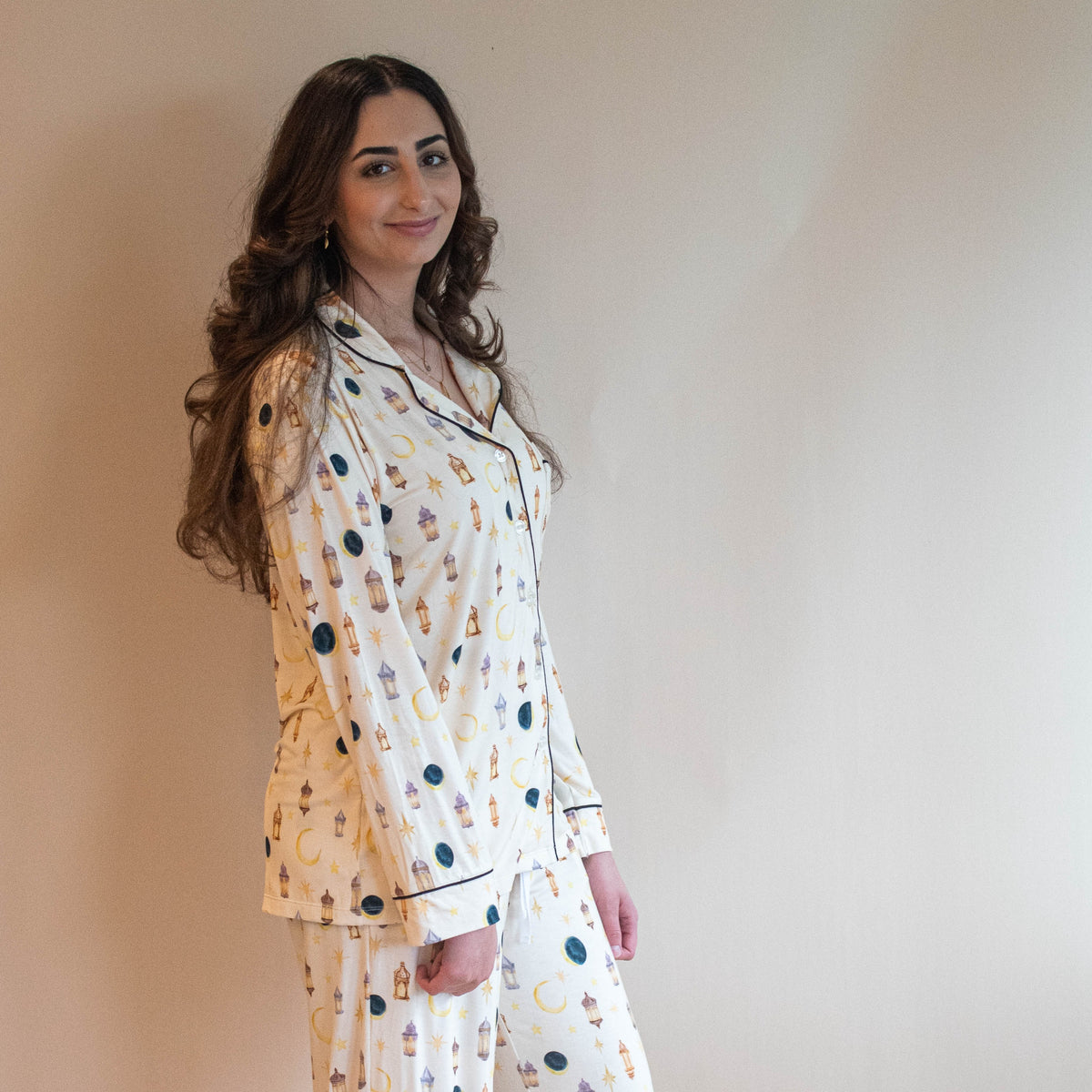 woman standing in pjs looking at camera moon and star lanterns all over pajamas
