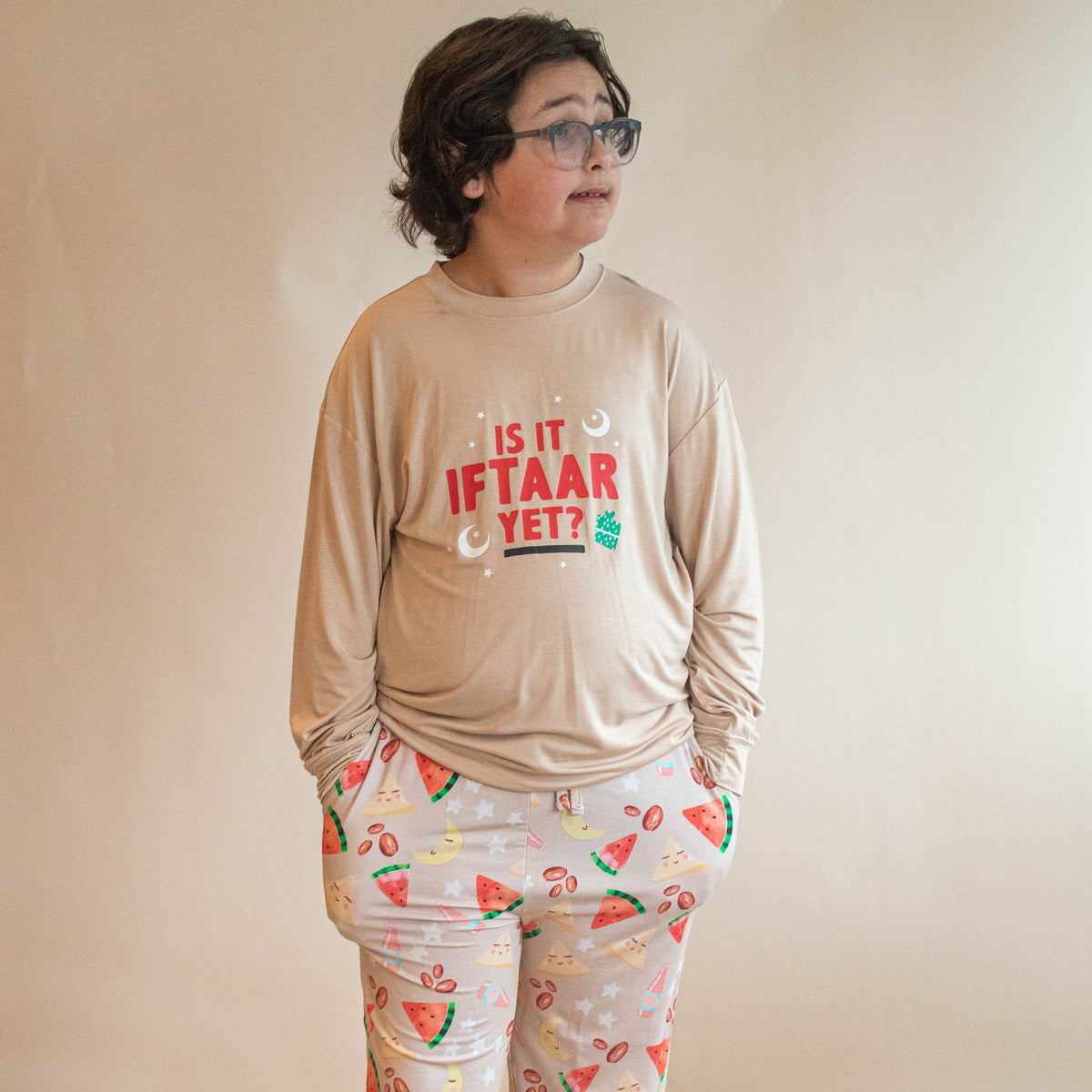 Boy wearing jogger set with "is it iftar yet" on his shirt and pants.  hands in pockets