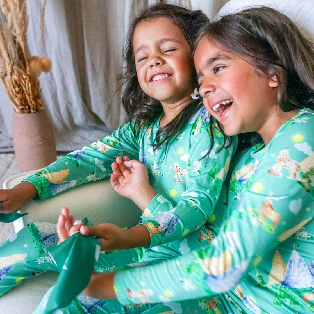 two girls giggling while wearing pajamas.
