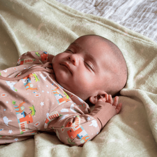 Baby in a brown outfit crawling on a carpeted floor with a teepee in the background