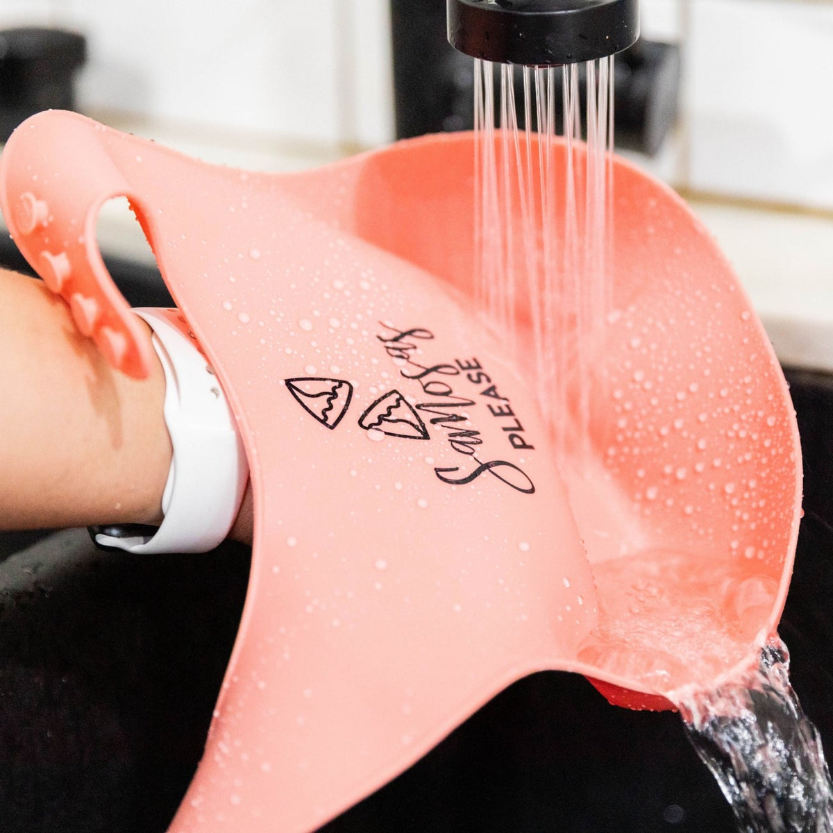 photo of &quot;rosie&quot; which is our pink color, samosas please bib being washed under a sink to show the ease of washing it.